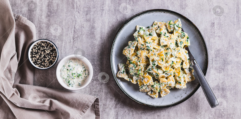 Скачать Макароны в сливочном соусе из рикотты и шпината на тарелке на столешнице посмотреть веб-баннер фотосток Ozero