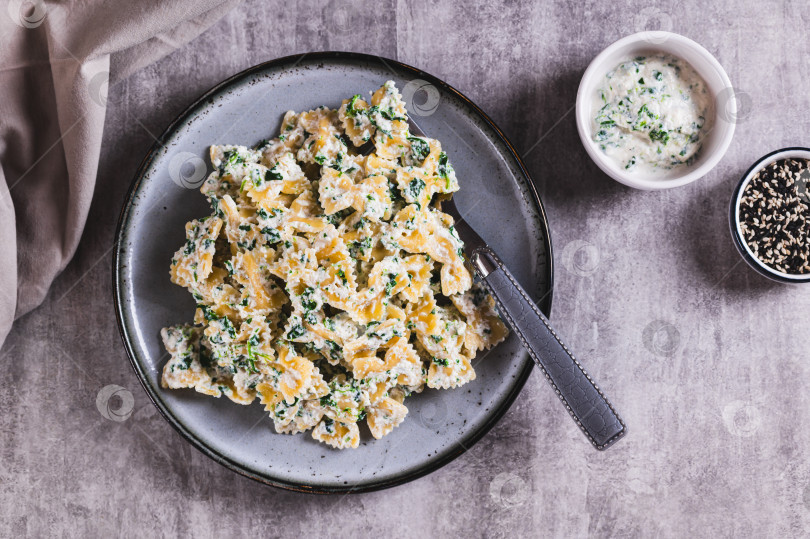 Скачать Аппетитные фарфалле с рикоттой и шпинатом на тарелке на столе вид сверху фотосток Ozero