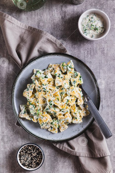 Скачать Паста в сливочном соусе из рикотты и шпината на тарелке, стоящей на столе в вертикальном положении фотосток Ozero