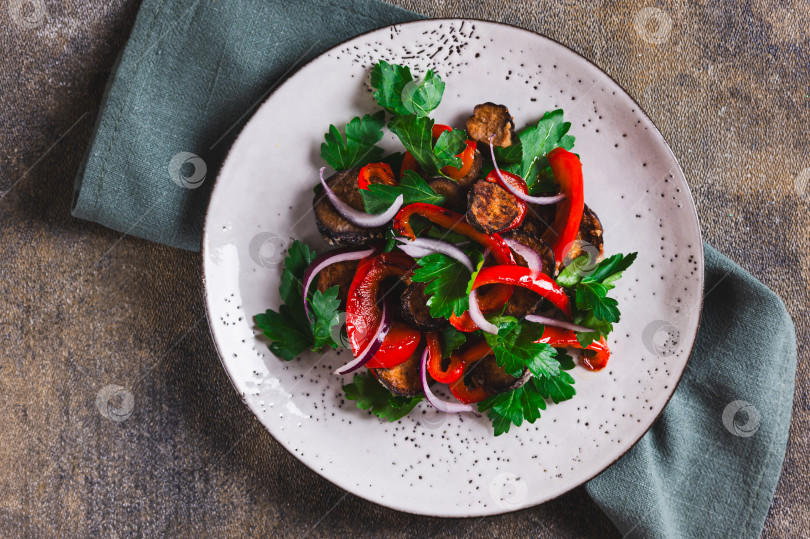 Скачать Теплый салат с жареными баклажанами, болгарским перцем, луком и зеленью крупным планом на тарелке, вид сверху фотосток Ozero