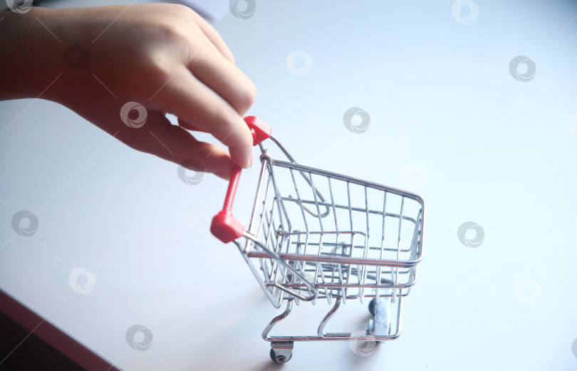 Скачать Маленькая тележка для покупок в детской руке. Крупный план фотосток Ozero