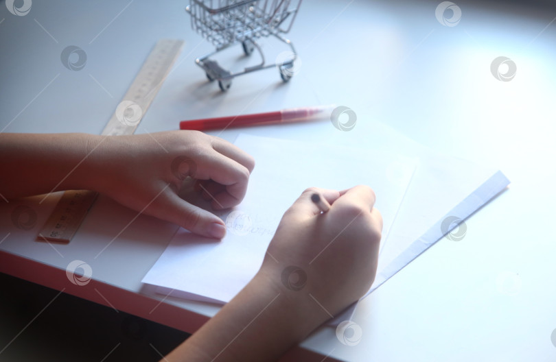 Скачать Школьница пишет карандашом на бумаге фотосток Ozero