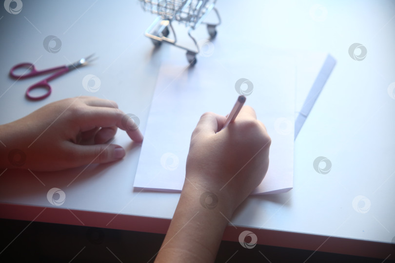 Скачать Школьница пишет карандашом на бумаге фотосток Ozero