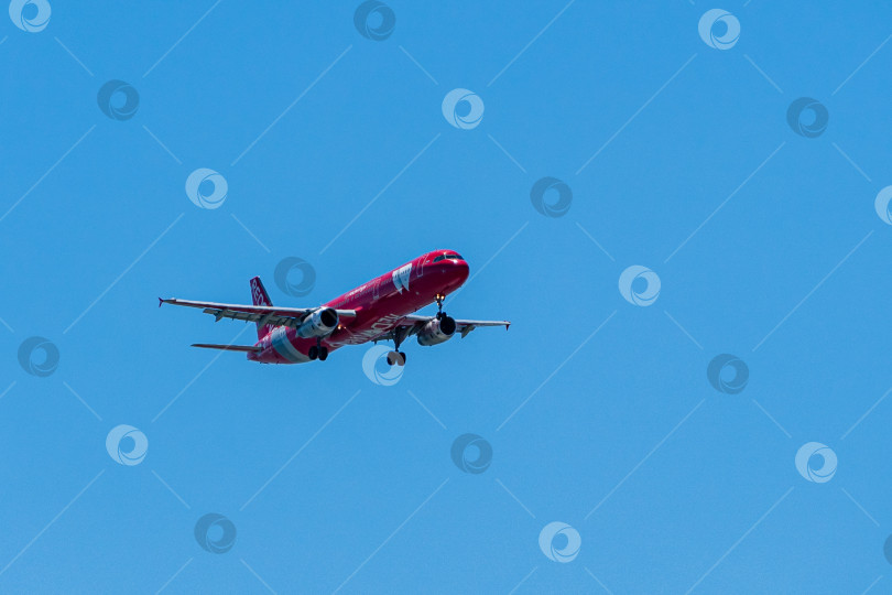 Скачать Самолет Airbus A321 в красной ливрее опускается на взлетно-посадочную полосу аэропорта Адлера на фоне голубого весеннего неба. Авиакомпания Red Wings. Шасси и закрылки самолета выпущены. фотосток Ozero