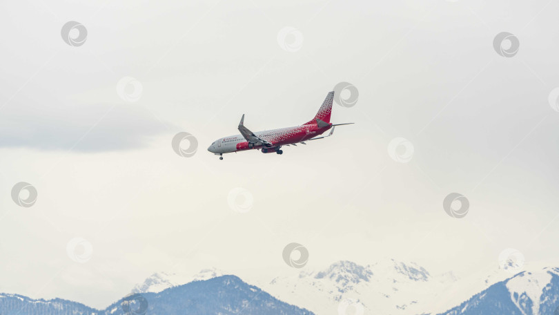 Скачать Boeing 737-800 авиакомпании "Россия" летит к взлетно-посадочной полосе на фоне заснеженных вершин Кавказских гор. Крупный план. Шасси и закрылки самолета выпущены. фотосток Ozero