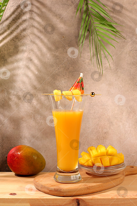 Скачать Домашний коктейль, сок или лимонад с кусочками манго и льдом на залитом солнцем кухонном столе. Концепция летней вечеринки. Рецепт освежающего летнего диетического напитка, детокс-диета и здоровый образ жизни, фотосток Ozero