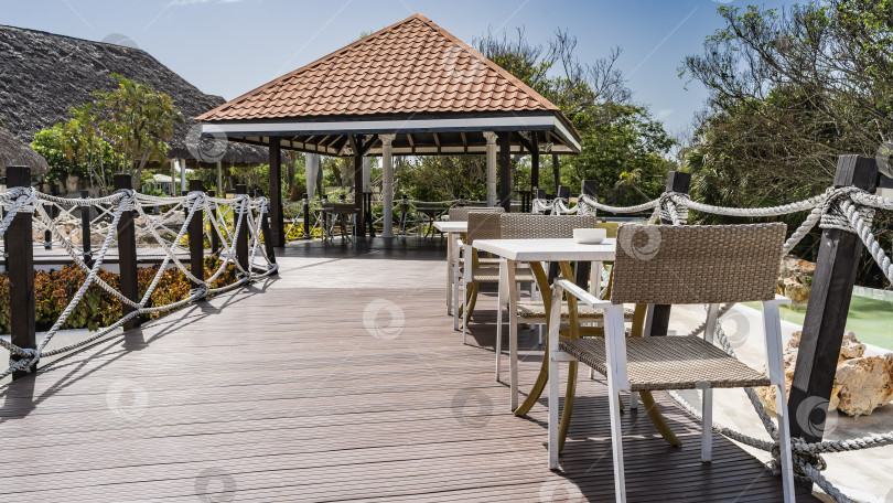 Скачать Зона отдыха в тропическом парке. На набережной установлены столы и стулья. фотосток Ozero