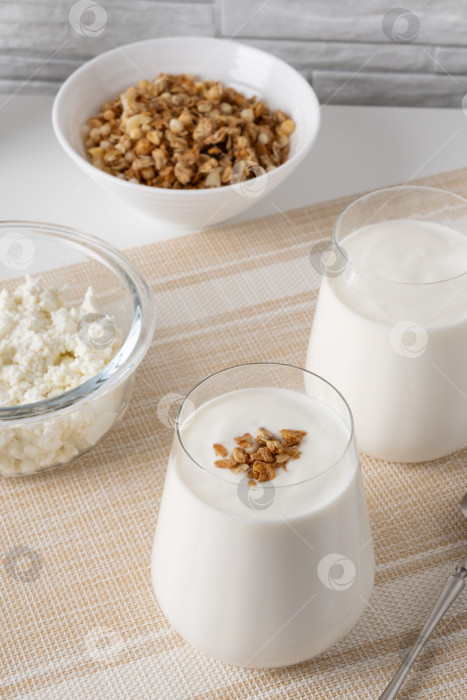 Скачать Кефир, пахта или йогурт, творог с гранолой. Йогурт в стакане на белом деревянном фоне. Холодный кисломолочный напиток с пробиотиками. Здоровье кишечника, кисломолочные продукты, концепция здоровой кишечной флоры фотосток Ozero