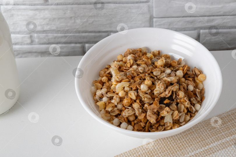 Скачать Тарелка с мюсли и молоком на столе на фоне серой кирпичной стены на кухне в утренние часы фотосток Ozero