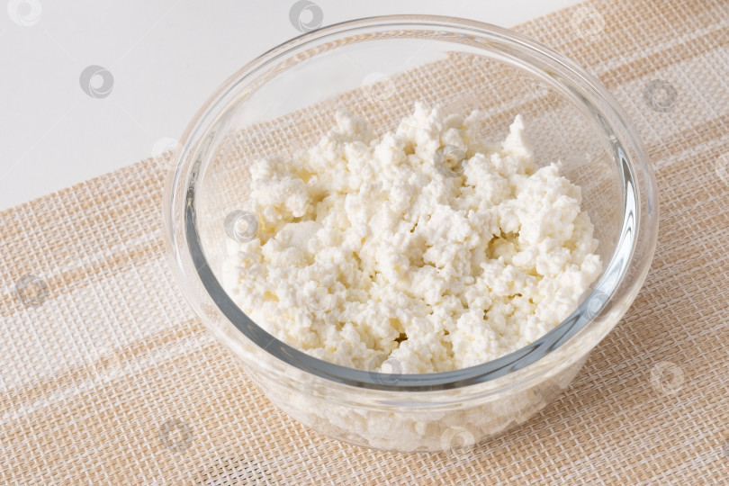Скачать Свежий творог, выложенный в прозрачную стеклянную посуду на светло-бежевую поверхность в дневное время фотосток Ozero