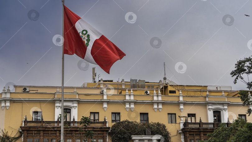 Скачать Национальный флаг Перу на флагштоке на фоне неба и облаков. фотосток Ozero