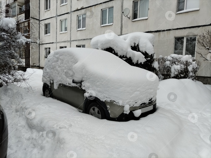 Скачать машина сильно занесена снегом, сверху большой сугроб, а рядом с ним большая машина. фотосток Ozero