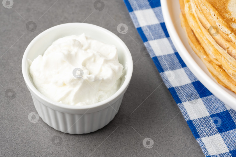 Скачать Взбитые сливки подаются в небольшой миске рядом со стопкой блинчиков на клетчатой салфетке фотосток Ozero