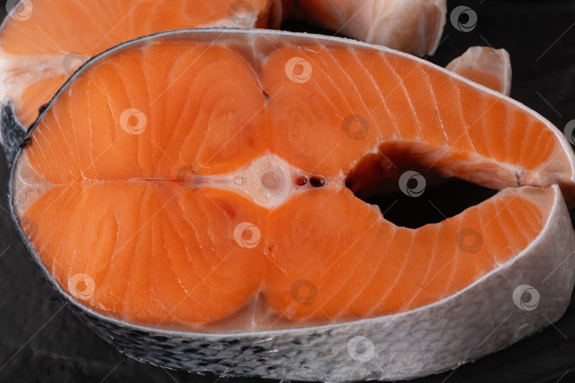 Скачать Нарезанное филе свежего лосося с оранжевой мякотью на черном фоне готово к приготовлению на кухне фотосток Ozero