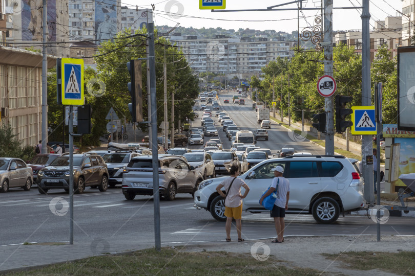 Скачать 24 августа 2025 года: Летняя уличная сцена в Новороссийске, Россия, с автомобилями, пешеходами и повседневной городской жизнью, отражающая городскую атмосферу в теплое время года. фотосток Ozero