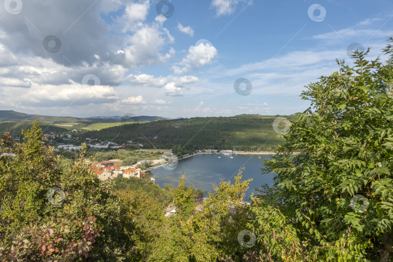 Скачать Набережная вдоль озера Абрау-Дюрсо со спокойной водой, зеленью и живописными окрестностями фотосток Ozero