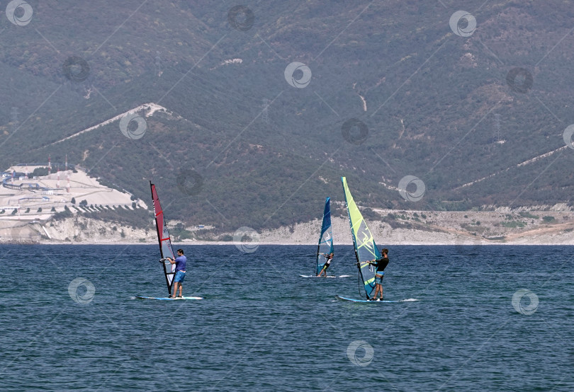 Скачать 24 августа 2025 года: Спортсмен занимается виндсерфингом на море недалеко от Новороссийска, Россия, с парусной доской и волнами, демонстрируя водные виды спорта, активный образ жизни и отдых на побережье. фотосток Ozero