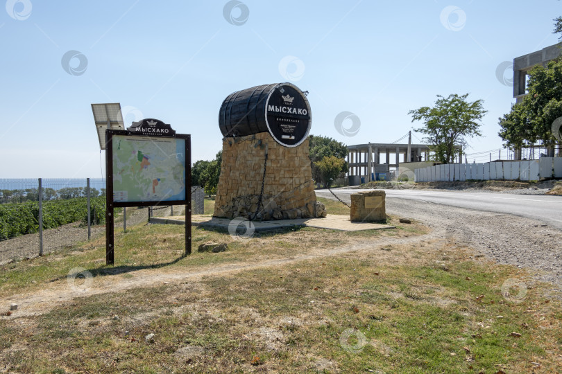 Скачать 24 августа 2025 года: Жанровая скульптура в виде бочки с вывеской винодельни в Мысхако, Россия, на фоне моря и гор на горизонте, символизирующая местное виноделие, туризм и прибрежный ландшафт. фотосток Ozero