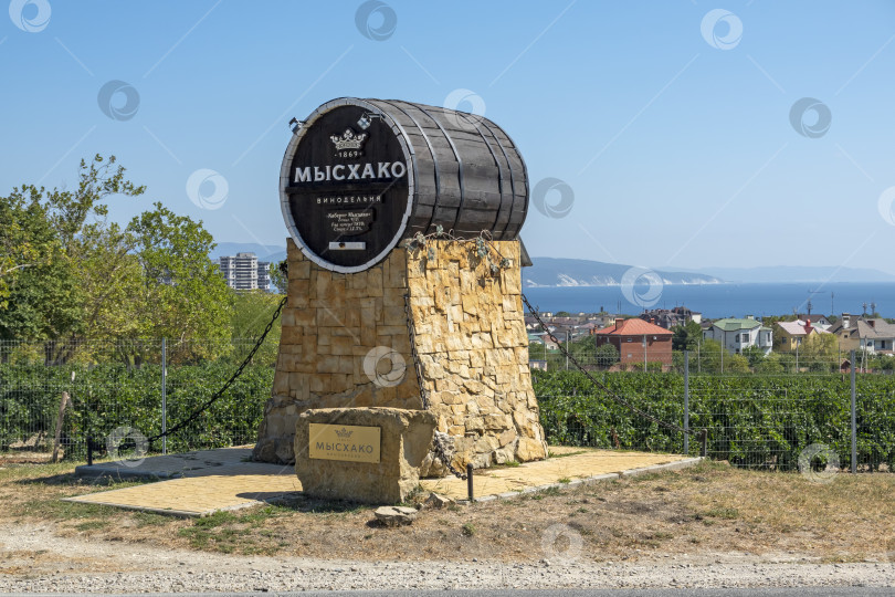 Скачать 24 августа 2025 года: Жанровая скульптура в виде бочки с вывеской винодельни в Мысхако, Россия, на фоне моря и гор на горизонте, символизирующая местное виноделие, туризм и прибрежный ландшафт. фотосток Ozero
