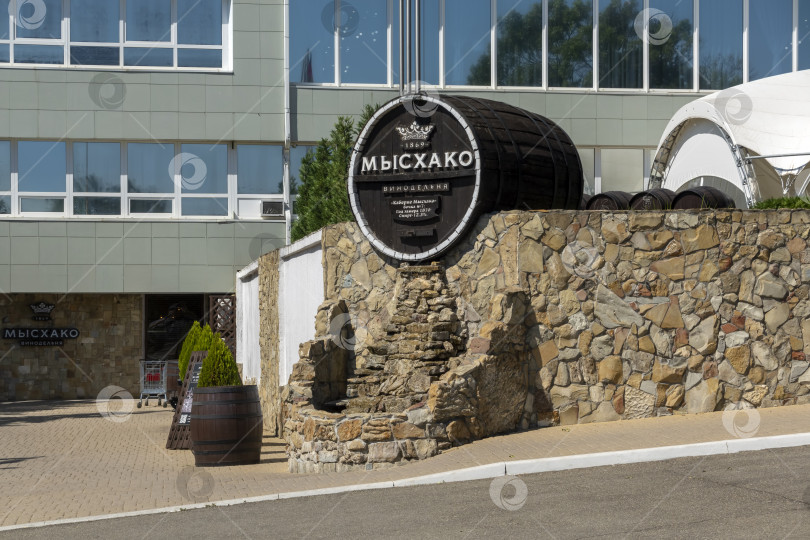 Скачать 24 августа 2025 года: Жанровая скульптура в виде бочки с вывеской винодельни в Мысхако, Россия, на фоне моря и гор на горизонте, символизирующая местное виноделие, туризм и прибрежный ландшафт. фотосток Ozero