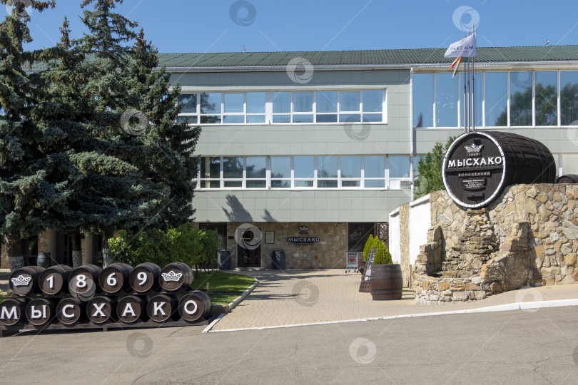 Скачать 24 августа 2025 года: Жанровая скульптура в виде бочки с вывеской винодельни в Мысхако, Россия, на фоне моря и гор на горизонте, символизирующая местное виноделие, туризм и прибрежный ландшафт. фотосток Ozero