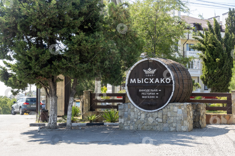 Скачать 24 августа 2025 года: Жанровая скульптура в виде бочки с вывеской винодельни в Мысхако, Россия, на фоне моря и гор на горизонте, символизирующая местное виноделие, туризм и прибрежный ландшафт. фотосток Ozero