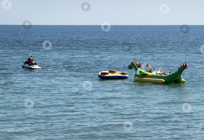 Скачать 24 августа 2025 года: Гидроцикл буксирует надувной банан по морю в Мысхако, Россия, демонстрируя пляжные развлечения, водные виды спорта и летний отдых на побережье. фотосток Ozero