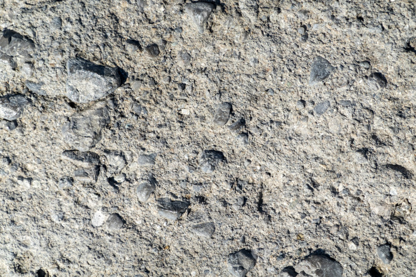 Скачать Крупный план текстуры натурального камня, детализирующий поверхность камня и его шероховатую структуру, подходит в качестве фона или абстрактного природного узора. фотосток Ozero