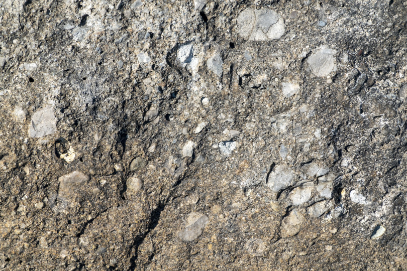 Скачать Крупный план текстуры натурального камня, детализирующий поверхность камня и его шероховатую структуру, подходит в качестве фона или абстрактного природного узора. фотосток Ozero