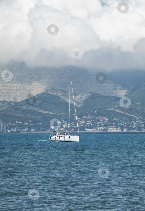 Скачать 24 августа 2025 года: Белая яхта Maverick с мачтой выходит из бухты Новороссийска, Россия, демонстрируя морской транспорт, парусный спорт для отдыха и прибрежную морскую активность на Черном море. фотосток Ozero