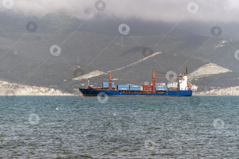 Скачать 24 августа 2025 года: Крупное грузовое судно заходит в порт Новороссийска, Россия, на Черном море, демонстрируя морской транспорт, промышленное судоходство и береговую инфраструктуру. фотосток Ozero