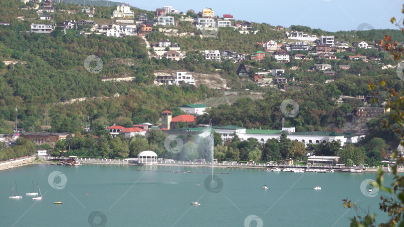 Скачать Набережная вдоль озера Абрау-Дюрсо со спокойной водой, зеленью и живописными окрестностями фотосток Ozero
