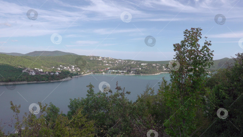 Скачать Набережная вдоль озера Абрау-Дюрсо со спокойной водой, зеленью и живописными окрестностями фотосток Ozero