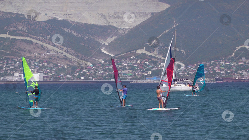 Скачать 24 августа 2025 года: Спортсмен занимается виндсерфингом в море недалеко от Новороссийска, Россия, с парусной доской и волнами, демонстрируя водные виды спорта, активный образ жизни и отдых на побережье. фотосток Ozero