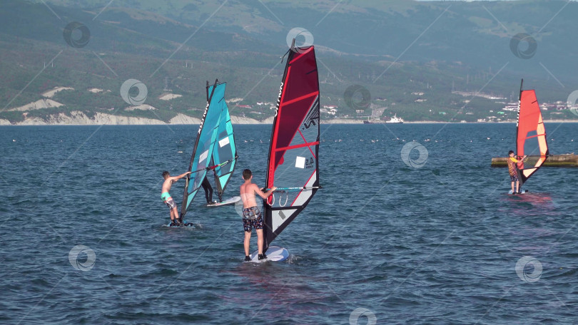 Скачать 24 августа 2025 года: Спортсмен занимается виндсерфингом на море недалеко от Новороссийска, Россия, с парусной доской и волнами, демонстрируя водные виды спорта, активный образ жизни и отдых на побережье. фотосток Ozero