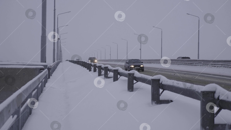 Скачать 28 декабря 2025 года, Барнаул, Россия. Заснеженная дорога с автомобилями, движущимися зимой, демонстрирующими городское движение, городской пейзаж и зимние городские условия. фотосток Ozero