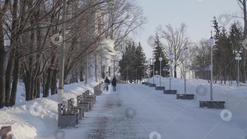 Скачать 28 декабря 2025 года, Барнаул, Россия. Зимой люди прогуливаются по центральной городской аллее, наслаждаясь заснеженными городскими улицами, сезонными мероприятиями на свежем воздухе и городским пейзажем. фотосток Ozero