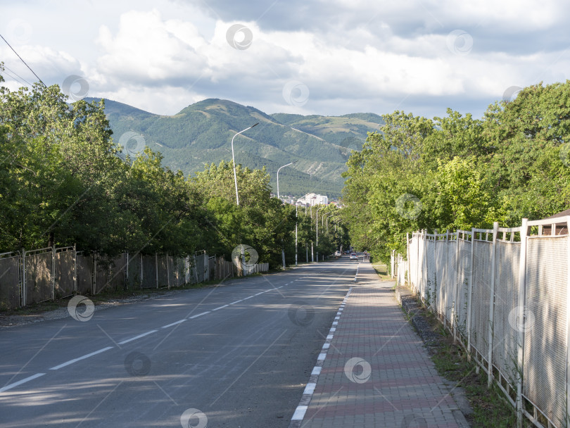 Скачать Асфальтированная улица, тянущаяся к горам на горизонте, сочетает сельскую инфраструктуру с живописным природным ландшафтом и далекими горными пейзажами фотосток Ozero