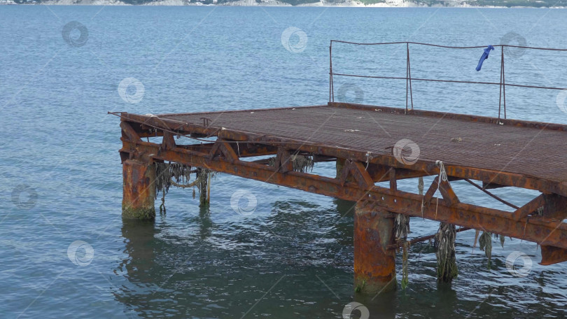 Скачать Вид на Черное море со старым ржавым металлическим пирсом, горы и небо. фотосток Ozero