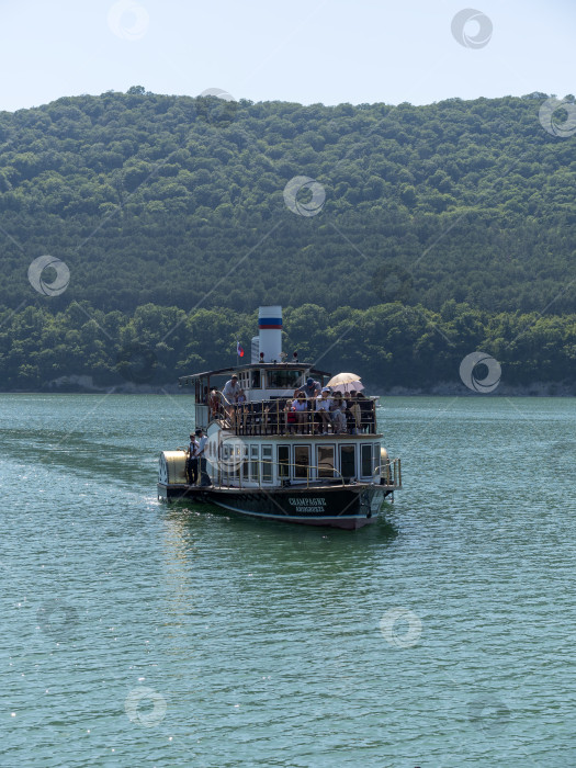 Скачать 19 августа 2025 года пассажирский теплоход "Шампань" причаливает к берегу озера Абрау-Дюрсо, окруженного спокойной водой и живописным ландшафтом фотосток Ozero