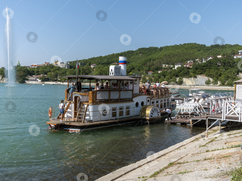 Скачать 19 августа 2025 года пассажирский теплоход "Шампань" причаливает к берегу озера Абрау-Дюрсо, окруженного спокойной водой и живописным ландшафтом фотосток Ozero
