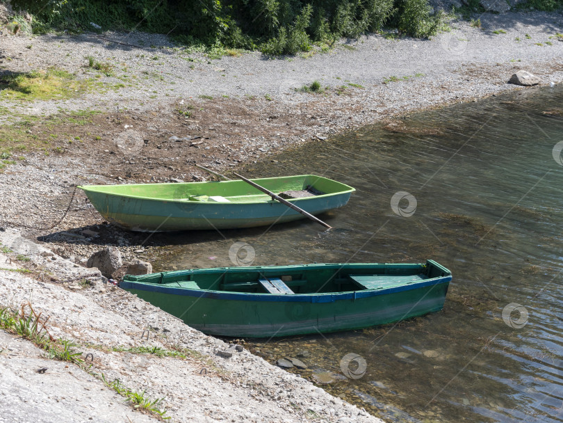 Скачать У берега, окруженные спокойной водой и зеленью, стоят две деревянные лодки. фотосток Ozero