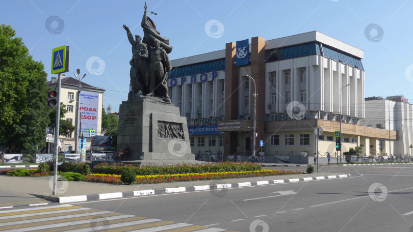 Скачать 12 августа 2025 года: Площадь Свободы в Новороссийске, Россия, центральное общественное пространство, где люди передвигаются по городу в лучах летнего солнца. фотосток Ozero