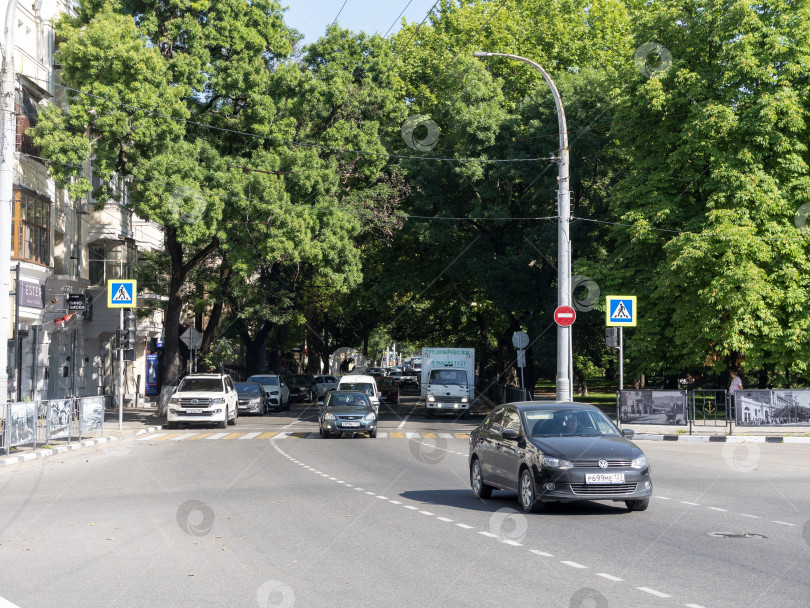 Скачать 12 августа 2025 года: Площадь Свободы в Новороссийске, Россия, центральное общественное пространство, где люди передвигаются по городу в лучах летнего солнца. фотосток Ozero