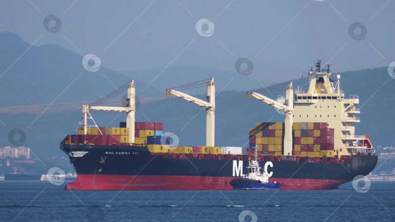 Скачать 24 августа 2025 года: Крупное грузовое судно заходит в порт Новороссийска, Россия, на Черном море, демонстрируя морской транспорт, промышленное судоходство и береговую инфраструктуру. фотосток Ozero