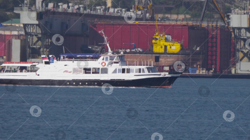 Скачать 12 августа 2025 года: Белая моторная лодка возле порта Новороссийск, Россия, с отдыхающими на борту людьми. фотосток Ozero