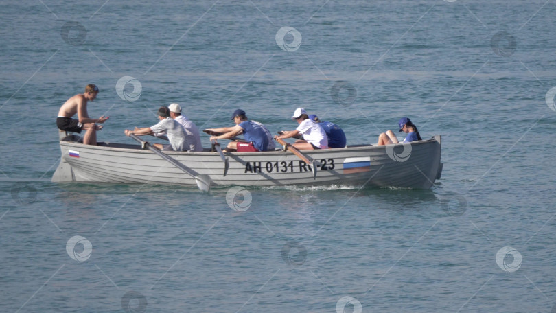 Скачать 12 августа 2025 года: Гребная лодка с подростками тренируется на воде фотосток Ozero