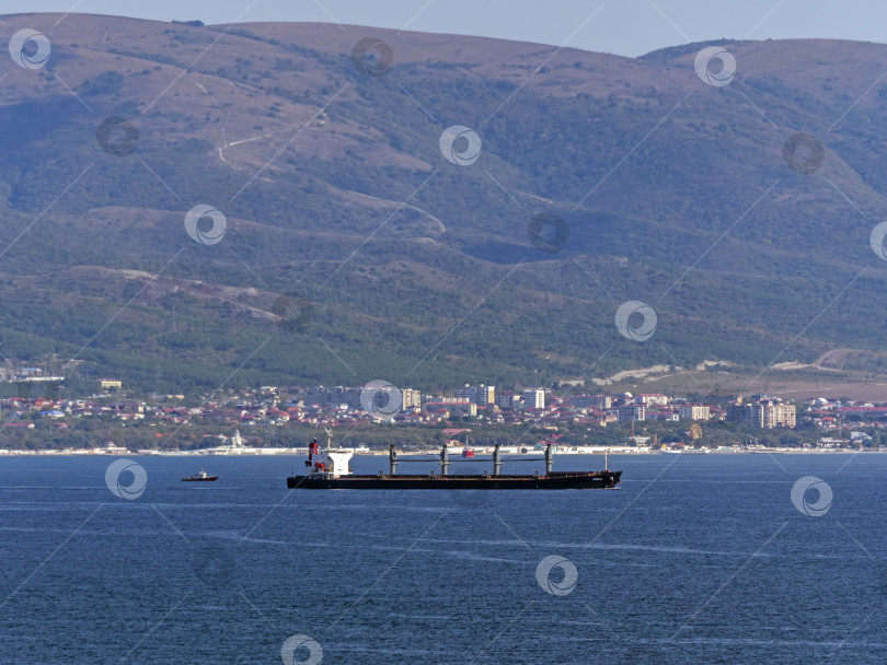 Скачать 12 августа 2025 года: Грузовое судно EIDER покидает порт Новороссийск, Россия. Чистое небо, спокойное море, промышленная гавань фотосток Ozero