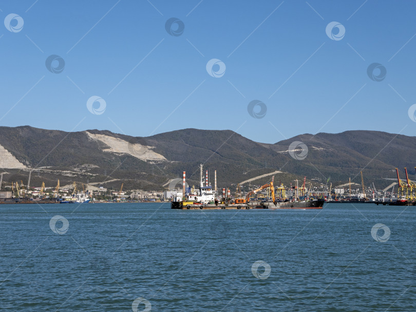 Скачать 22 августа 2025 года, вид порта Новороссийск, Россия, с грузовыми судами и кранами на побережье. Промышленный морской пейзаж на Черном море фотосток Ozero