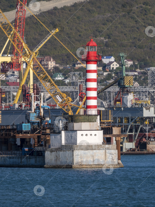 Скачать 22 августа 2025 года маяк у входа в порт Новороссийск, Россия, красно-белый на побережье Черного моря. Навигационное оборудование в порту фотосток Ozero